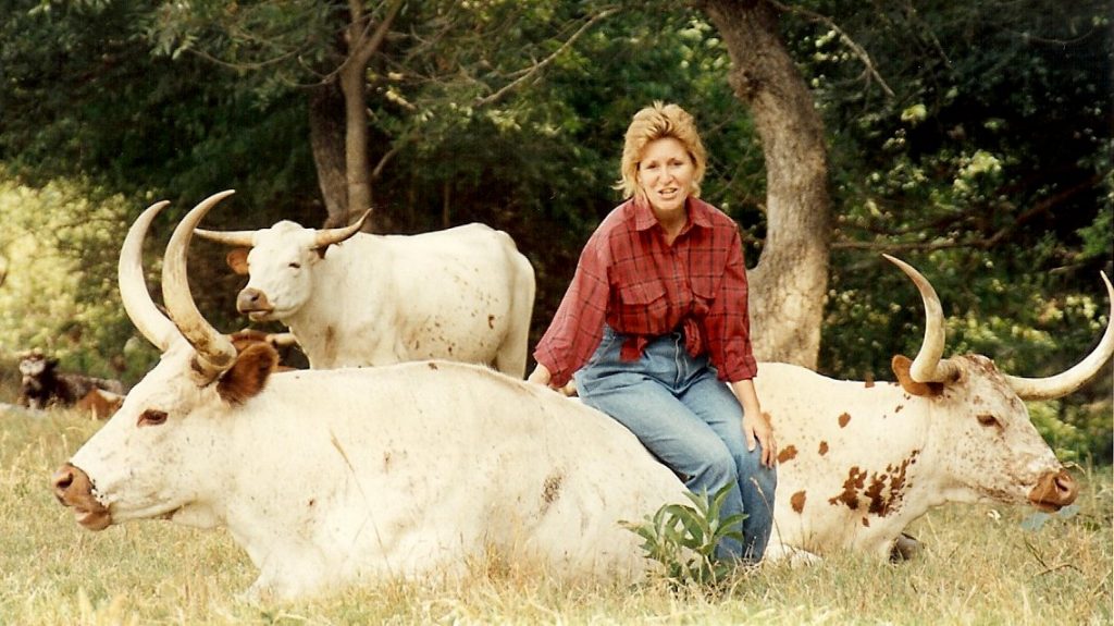 Barbara Franklin Schmidt, sitting on a longhorn cow